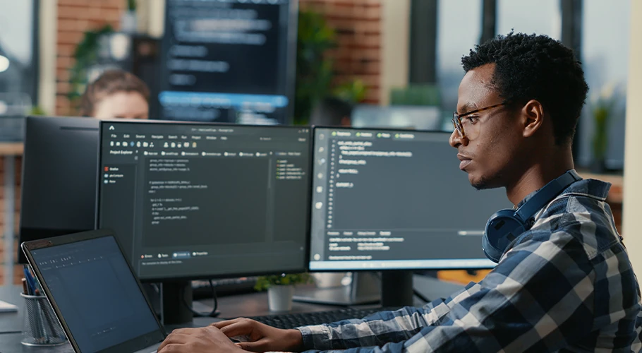 guy coding in front of two screen